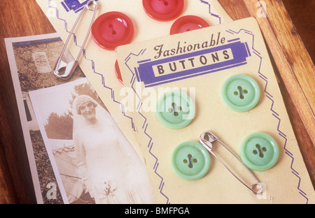 Close up de rouge et vert pâle sur les boutons se trouvant sur des cartes anciennes photos sépia de jeune femme en robe nuptiale 1920 Banque D'Images