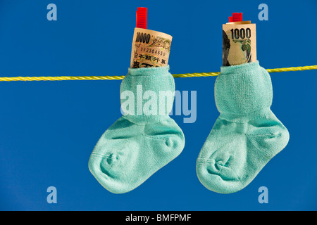 Chaussettes bébé sur corde avec notes Yen du Japon. Banque D'Images