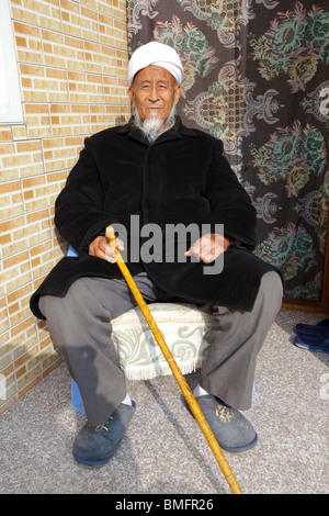 Personnes âgées Salar homme avec un bâton de marche, Salar Xunhua comté autonome, Haidong préfecture, province de Qinghai, Chine Banque D'Images