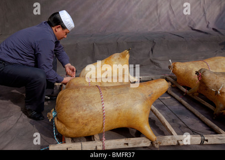 Salar man making un radeau en liant ensemble peau de mouton grillé, Salar Xunhua comté autonome, la Préfecture de Haidong, Qinghai, Chine Banque D'Images