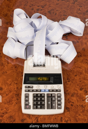 Calculatrice de bureau avec ordinateur de rayures. Symbole pour les frais, les charges, les revenus et les profits.