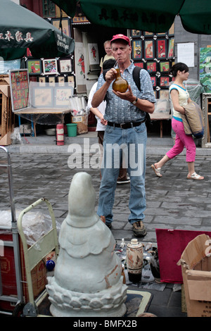 Examen touristiques caucasienne ses achats, marché d'antiquités de Panjiayuan, Beijing, Chine Banque D'Images