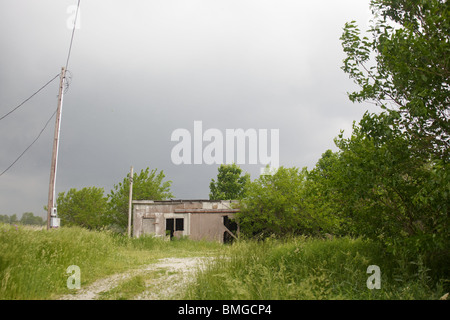 Une remise se trouve à la fin d'une route de gravier comme une tempête dans la région. Banque D'Images