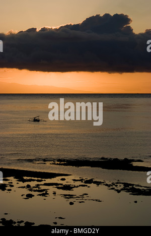 Comme le soleil se lève sur Amed, Bali, des pêcheurs dans leurs petites embarcations appelées jukung retour à terre pour décharger leurs prises de la journée. Banque D'Images