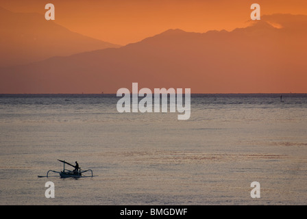 Comme le soleil se lève sur Amed, Bali, des pêcheurs dans leurs petites embarcations appelées jukung retour à terre pour décharger leurs prises de la journée. Banque D'Images