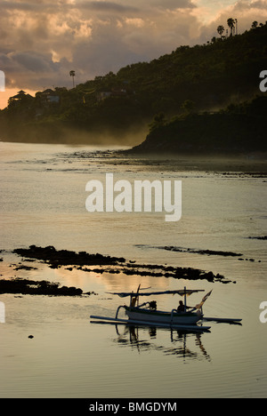 Comme le soleil se lève sur Amed, Bali, des pêcheurs dans leurs petites embarcations appelées jukung retour à terre pour décharger leurs prises de la journée. Banque D'Images