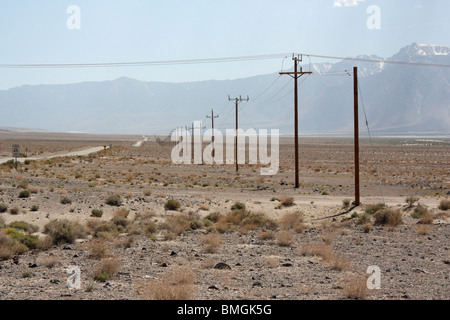 Ligne de poteaux télégraphiques disparaissant dans la distance dans un vaste désert californien Banque D'Images