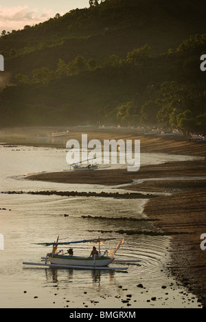 Comme le soleil se lève sur Amed, Bali, des pêcheurs dans leurs petites embarcations appelées jukung retour à terre pour décharger leurs prises de la journée. Banque D'Images