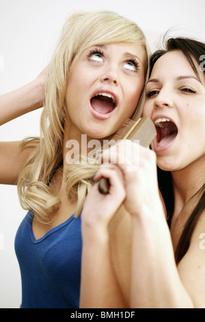 Teenage Girls singing into hairbrush modèle publié. Banque D'Images