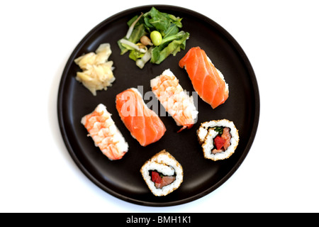 Sélection de style japonais, le poisson cru et riz Sushi servi sur une plaque noire avec des baguettes isolé sur un fond blanc avec un chemin de détourage Banque D'Images