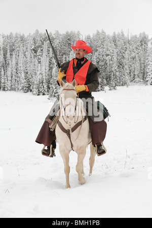 Cowboy hunter équitation cheval blanc dans la neige la chasse au fusil Banque D'Images