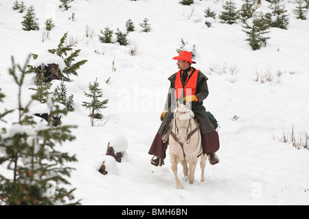 Cowboy hunter équitation cheval blanc dans la chasse neige Banque D'Images