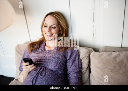 Pregnant woman typing on mobile Banque D'Images