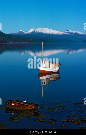 Petit bateau de pêche ancré dans le fjord norvégien avec petite barque Banque D'Images