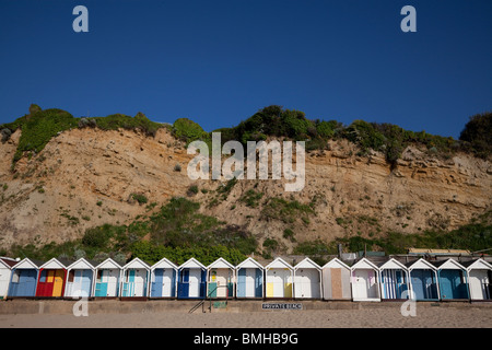 Rangée de cabines de plage lumineux sous la falaise sur la plage de Swanage. Banque D'Images