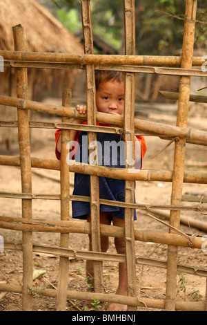 Enfants Hmong à travers une clôture dans un petit village entre Pakbeng et Luang Prabang, Laos. Banque D'Images