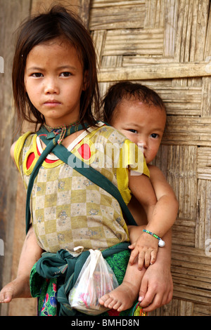 Enfants Hmong portant son frère dans un petit village entre Pakbeng et Luang Prabang, Laos. Banque D'Images