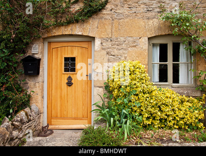Porte avant en bois et fenêtre sur un typique en pierre de Cotswold House en Angleterre, Royaume-Uni Banque D'Images