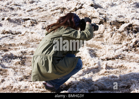 Femme photographe prenant pictues de la ceinture croûte de sel en raison des fortes pluies de l'hiver au bassin de Badwater dans la vallée de la mort. Banque D'Images