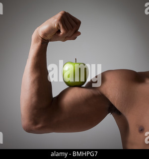 Green Apple perché sur un bras musclé fléchie Banque D'Images