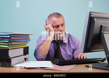 Surchargés de l'homme assis à son bureau Banque D'Images