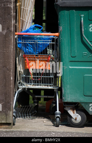 Chariot d'achat abandonné plein de bêtises à côté d'une grande poubelle à Édimbourg, en Écosse. Banque D'Images