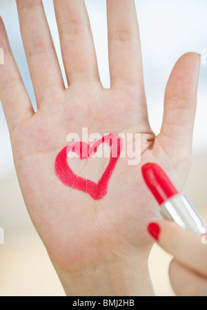 Coeur rouge dessiné sur la main avec le rouge à lèvres Banque D'Images