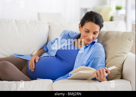 Pregnant woman reading on couch Banque D'Images