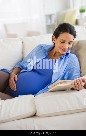 Pregnant woman reading on couch Banque D'Images