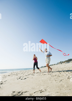 Couple flying kite on beach Banque D'Images