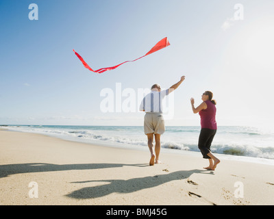 Couple flying kite on beach Banque D'Images