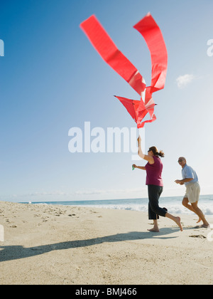 Couple flying kite on beach Banque D'Images