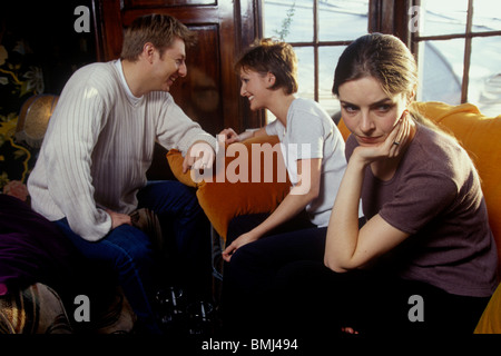 Un couple ayant un verre ensemble dans un bar avec une femme au premier plan à la marre Banque D'Images