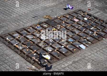 Couvercle de trou d'extérieur d'une entreprise de location de voiture, couverte de mégots et de déchets de la part de personnes de vider leur voiture de cendriers. Banque D'Images