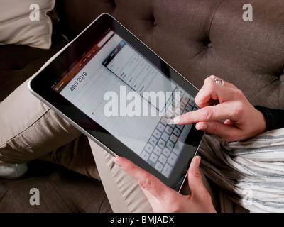 Femme sur la table à l'aide d'écran tactile Apple iPad tablet computer mains libre Banque D'Images
