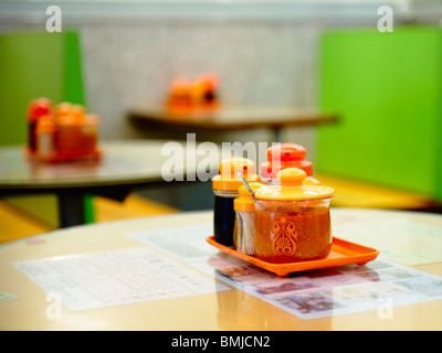 Source traditionnel situé sur une table de dîner à Hong Kong, à l'appareil principal d'objectif dans l'avant-plan, deux ensembles flous dans le dos. Banque D'Images