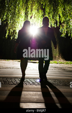 Couple crossing road at night Banque D'Images