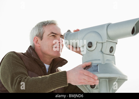 Homme regardant à travers un télescope Banque D'Images