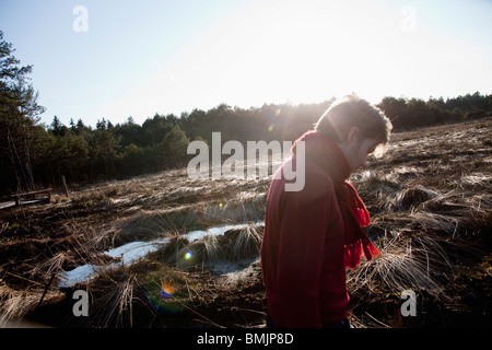 Homme marchant à travers la forêt ensoleillée scene Banque D'Images