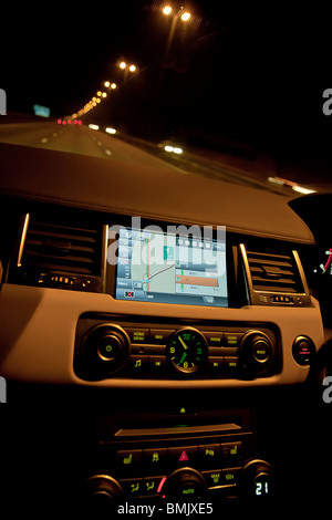 L'intérieur du Range Rover voiture montrant sat nav et compose sur planche de bord la nuit sur l'autoroute. UK Banque D'Images