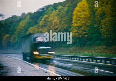 Grand chariot de vitesses élevées le long de l'automne pluvieux humide automne route scene Banque D'Images