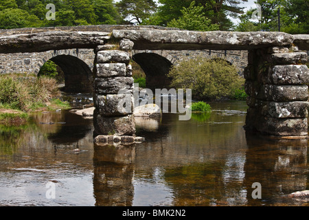 La cité médiévale Clapper Bridge avec le pont routier sur l'Est de la rivière Dart à Postbridge dans le Dartmoor, dans le Devon. Banque D'Images