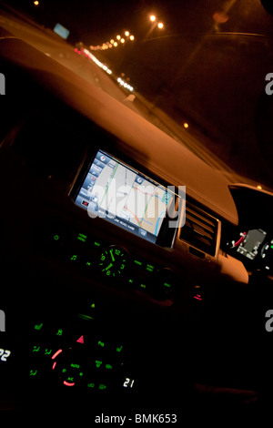 L'intérieur du Range Rover voiture montrant sat nav et compose sur planche de bord la nuit sur l'autoroute à la circulation. UK Banque D'Images