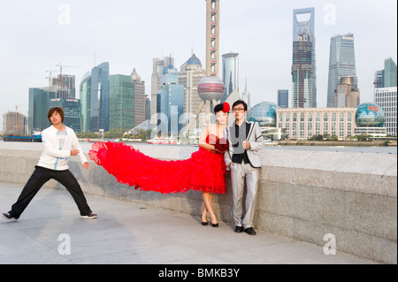 Jeune couple de jeunes mariés ayant des photos prises sur le Bund à l'encontre de la ville, Shanghai, Chine Banque D'Images