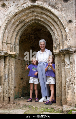 Afrique, Kenya, Malindi. Grand-mère et des jumeaux se tenir dans une fenêtre sur le ruines de Gedi, une ville arabo-africain du 15ème siècle. Banque D'Images