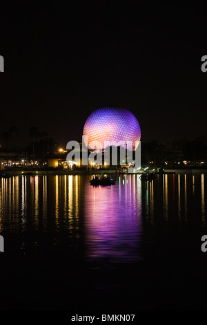 Dôme géodésique de Spaceship Earth attraction éclairé avec des lumières violettes se reflète sur le lac de nuit dans Walt Disney's Epcot Center Banque D'Images