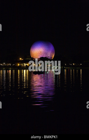 Dôme géodésique de Spaceship Earth attraction éclairé avec des lumières violettes se reflète sur le lac de nuit dans Walt Disney's Epcot Center Banque D'Images