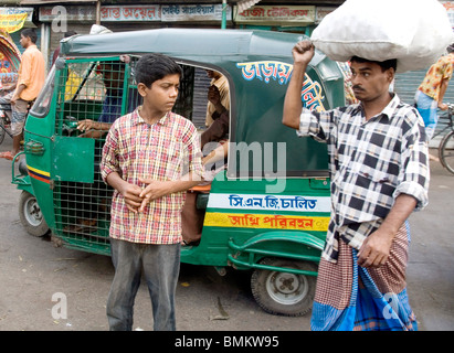 Scène de rue musulman et le garçon debout à tempo vert auto rickshaw hors du côté de bateau Sadarghat ; terminal ; Bangladesh Dhaka Banque D'Images