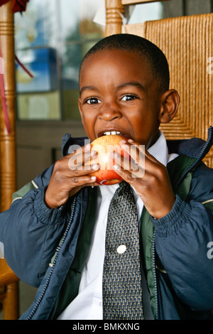 African American boy portant chemise blanche et cravate jacket eating apple en face de Cracker Barrel Store and Restaurant Florida M. © Myrleen Pearson Banque D'Images