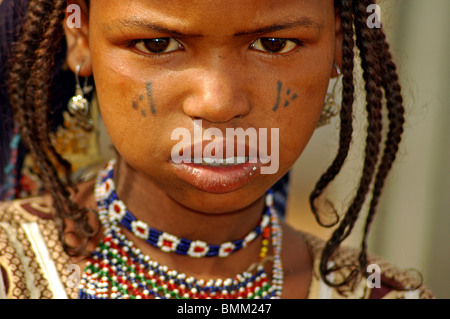 Le Niger, Niamey, petite fille africaine dans des vêtements traditionnels et une coiffe noire, avec des scarifications tribales sur son visage Banque D'Images